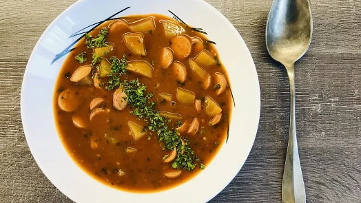 Mísa s frankfurtskou polévkou se šunkami, bramborami a bylinkami.