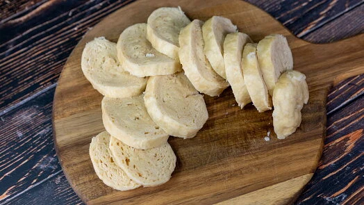 Nakrájené knedlíky na dřevěném prknu pro recept.