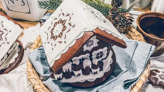 Tradiční perníková chaloupka s bílým cukrovou výzdobou v košíku.