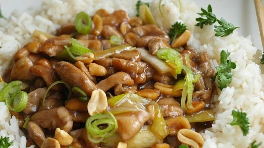 Hotovo kuřecí kung pao s rýží, oříšky a cibulkou.