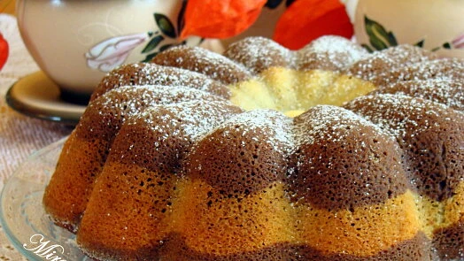 Jogurtová bábovka s vrstvami čokolády a vanilky posypaná cukrem.