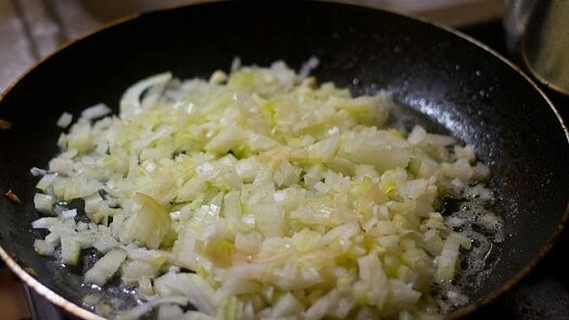 Smažené nakrájené cibule v pánvi pro recept na kotlety.