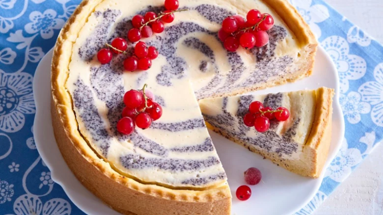 Nepečený tvarohový cheesecake s zakysanou smetanou ozdobený červenými brusinkami.