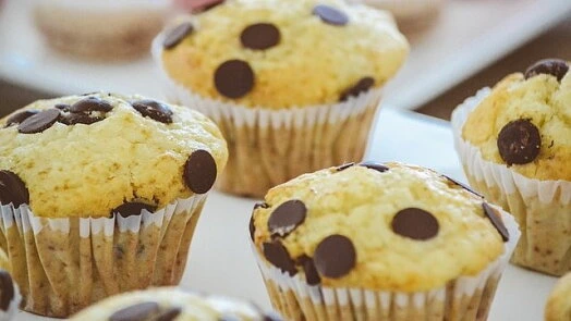 Zlatohnědé muffiny s čokoládovými kousky v papírových formách.
