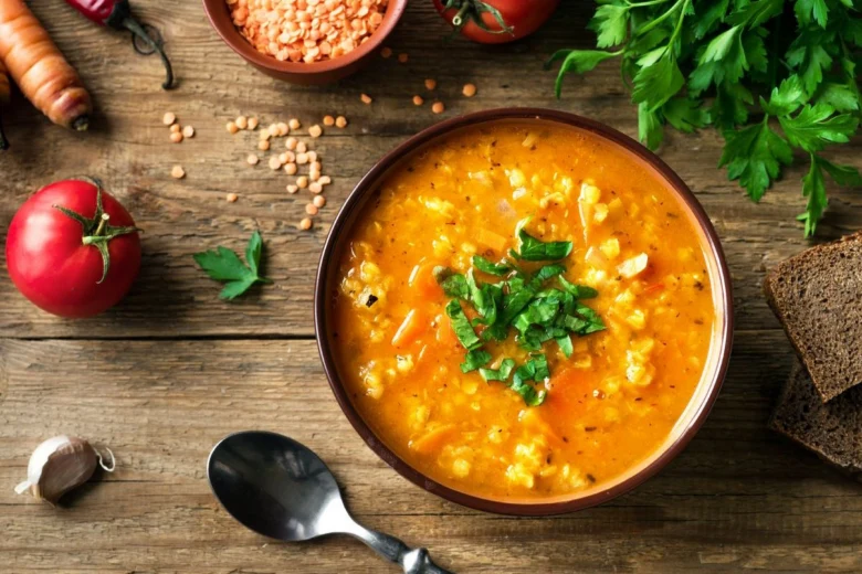 Miska červené čočkové polévky s petrželkou a surovými ingrediencemi