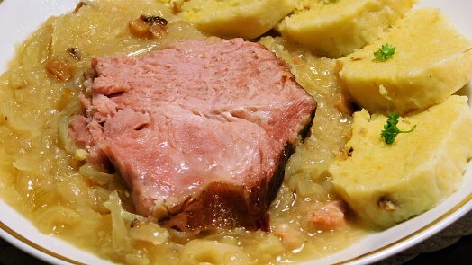 Tradiční české vepřo s knedlíkem a zelím na talíři.