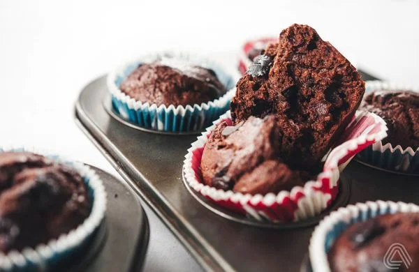 Čokoládové muffiny s ovocem v papírových formách na plechu.